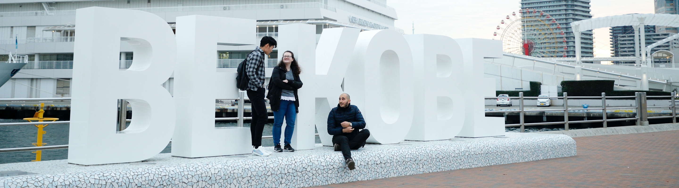 神戸メリケンパークに設置された「BE KOBE」のオブジェに外国人留学生3人で話をしている様子