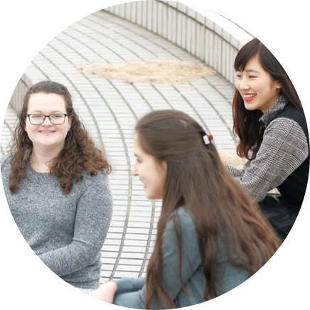 外国人留学生3人で外の階段に座って話をしている様子