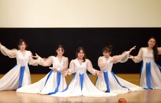 ステージ上で民族衣装を着ている大学生たちの踊り様子