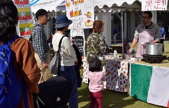 行列に並ぶ人から見た屋台で外国籍の方が料理を販売する様子